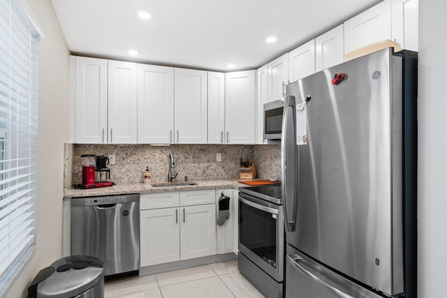 kitchen with stainless steel appliances, sink, tasteful backsplash, and white cabinetry