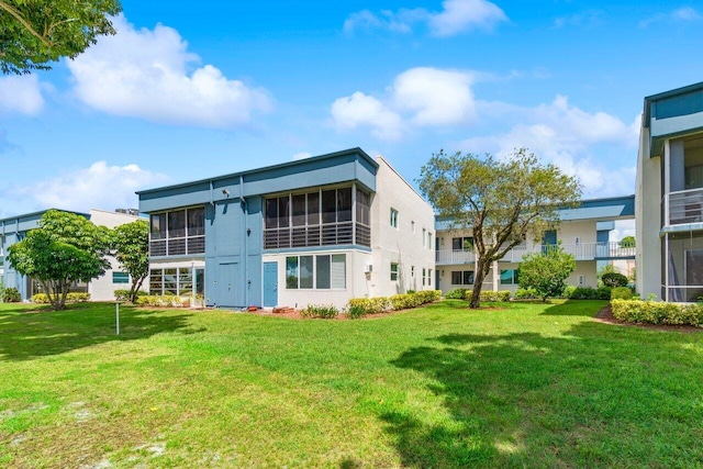 rear view of property featuring a yard and a sunroom