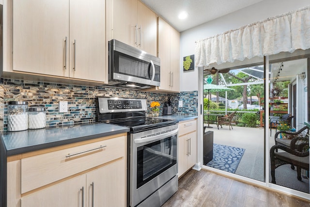 kitchen featuring stainless steel appliances, backsplash, hardwood / wood-style flooring, and light brown cabinetry