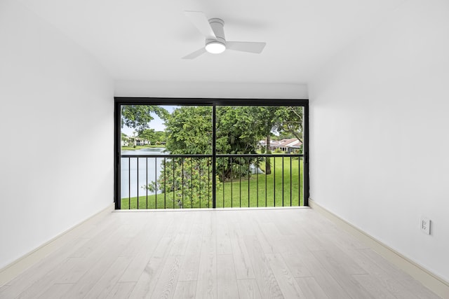 empty room featuring light wood-type flooring, a water view, and ceiling fan