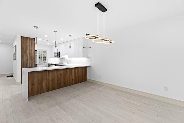 kitchen featuring kitchen peninsula, light hardwood / wood-style floors, and hanging light fixtures