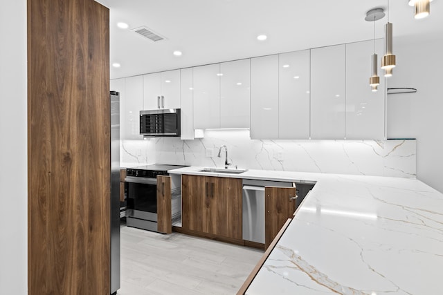 kitchen with range with electric cooktop, light stone countertops, hanging light fixtures, sink, and white cabinets