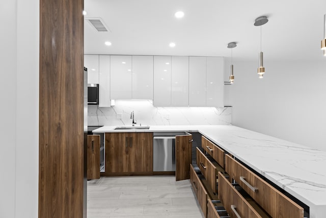 kitchen featuring white cabinetry, decorative light fixtures, sink, light hardwood / wood-style floors, and stainless steel dishwasher