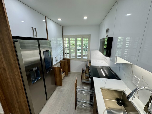 kitchen featuring light hardwood / wood-style floors, white cabinetry, tasteful backsplash, light stone countertops, and stainless steel refrigerator with ice dispenser