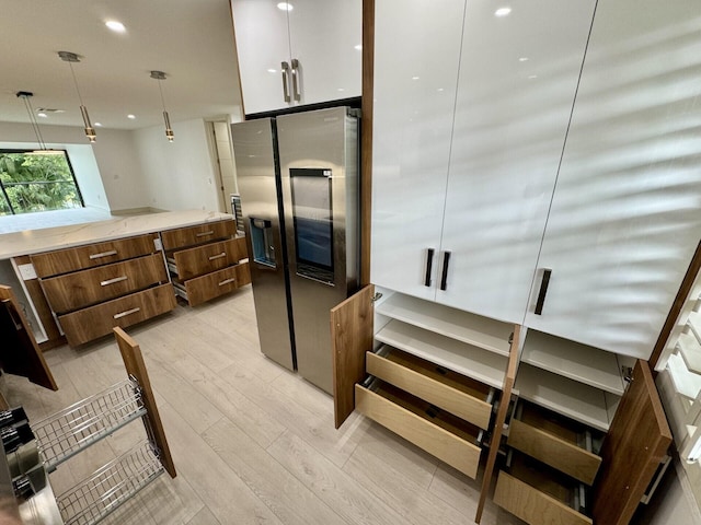 kitchen with pendant lighting, light hardwood / wood-style flooring, white cabinetry, and stainless steel fridge