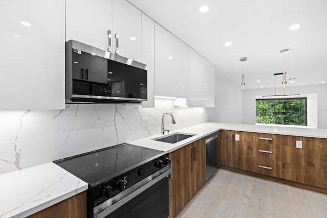 kitchen featuring light stone counters, white cabinetry, appliances with stainless steel finishes, sink, and light hardwood / wood-style floors