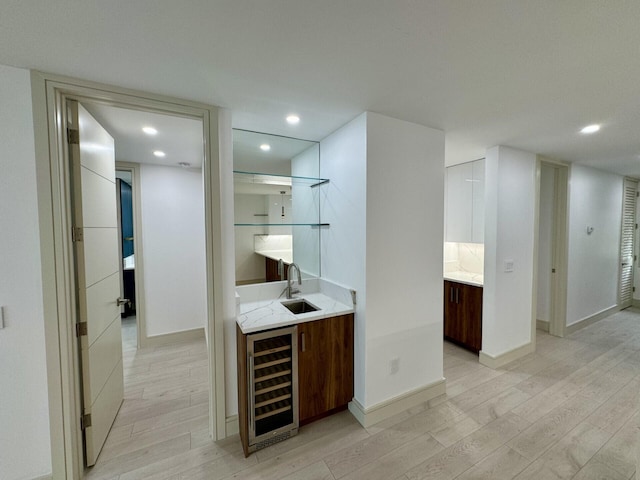 bar featuring light stone countertops, wine cooler, light hardwood / wood-style flooring, and sink