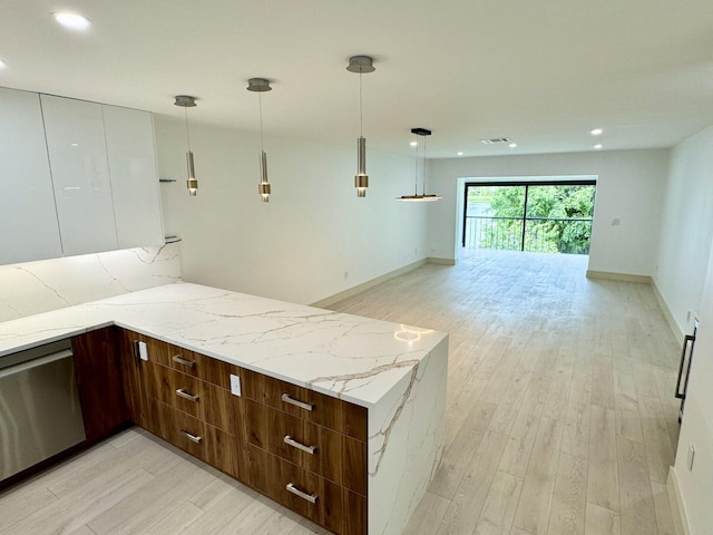 kitchen featuring kitchen peninsula, light stone counters, decorative light fixtures, stainless steel dishwasher, and light wood-type flooring