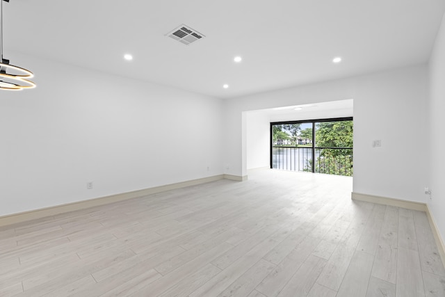 spare room featuring an inviting chandelier and light wood-type flooring