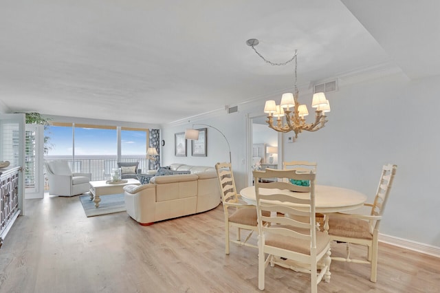 dining area with crown molding, an inviting chandelier, and light hardwood / wood-style flooring