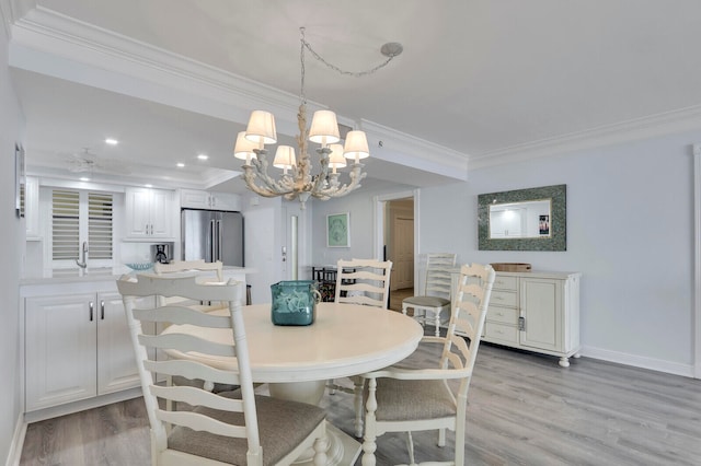 dining room featuring ornamental molding, light wood-type flooring, a chandelier, and sink