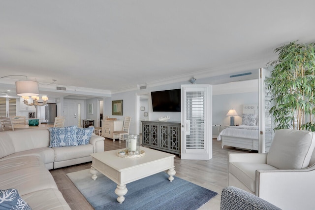 living room featuring wood-type flooring, crown molding, and a notable chandelier