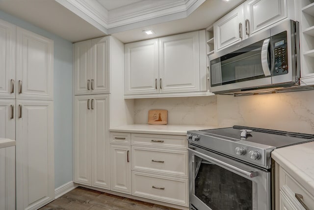 kitchen with dark hardwood / wood-style floors, white cabinetry, decorative backsplash, appliances with stainless steel finishes, and crown molding