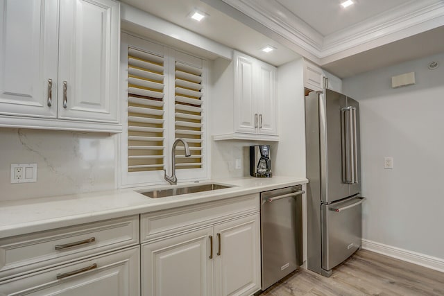 kitchen with white cabinets, sink, stainless steel appliances, crown molding, and light hardwood / wood-style floors