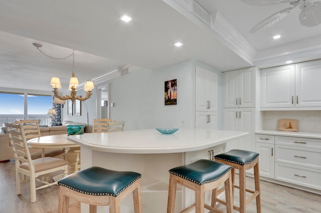 kitchen featuring hanging light fixtures, a chandelier, white cabinetry, crown molding, and light hardwood / wood-style floors