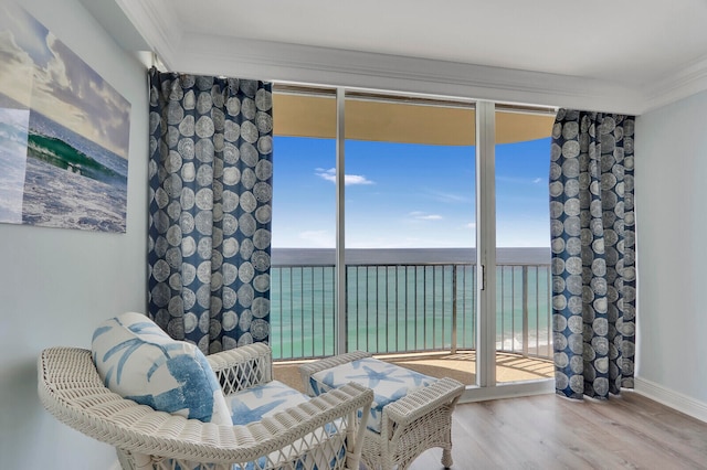 living area featuring wood-type flooring, crown molding, a water view, and a wealth of natural light