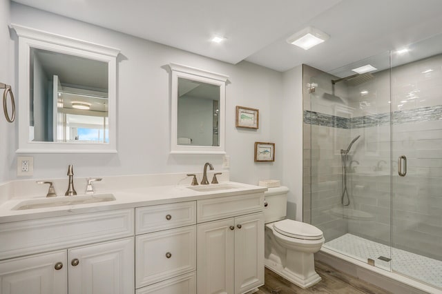 bathroom featuring hardwood / wood-style floors, vanity, toilet, and a shower with door