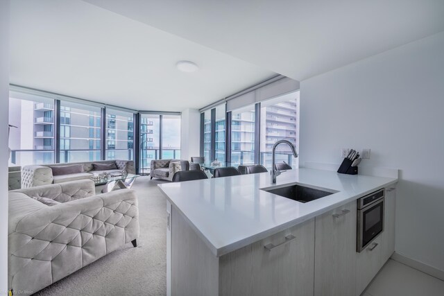 kitchen featuring oven, sink, light carpet, and kitchen peninsula