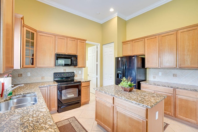 kitchen with a kitchen island, light stone countertops, black appliances, crown molding, and sink