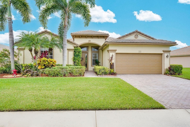 mediterranean / spanish home featuring a garage and a front lawn