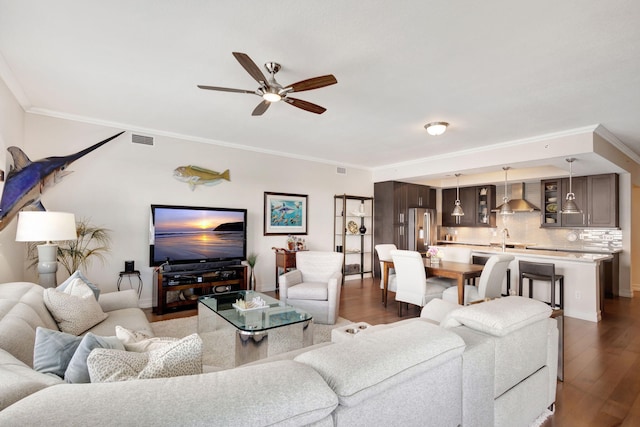 living room with ceiling fan, ornamental molding, sink, and dark hardwood / wood-style floors