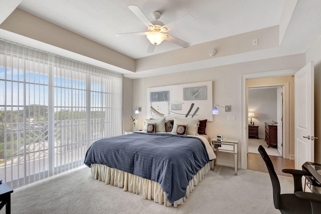 bedroom with ceiling fan, a tray ceiling, carpet floors, and access to exterior