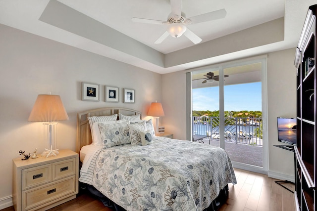 bedroom featuring hardwood / wood-style floors, a raised ceiling, access to exterior, and ceiling fan