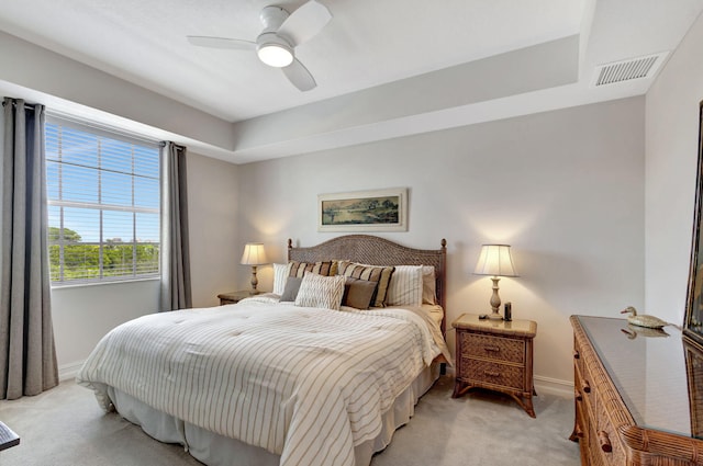 bedroom with ceiling fan, a raised ceiling, and light colored carpet