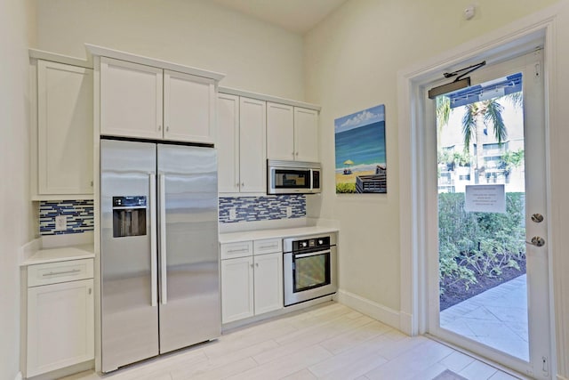 kitchen with white cabinetry, stainless steel appliances, and backsplash