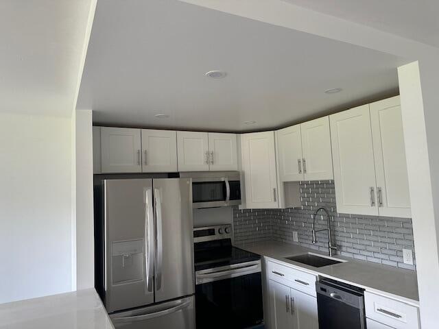 kitchen with stainless steel appliances, white cabinetry, and sink