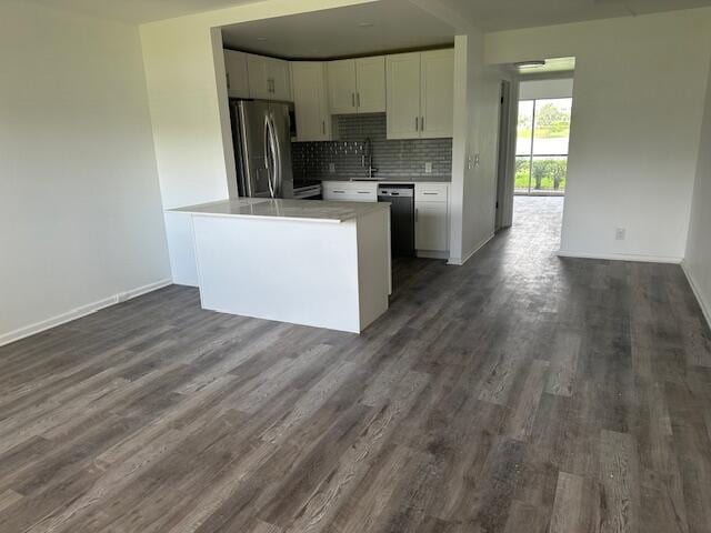 kitchen featuring appliances with stainless steel finishes, white cabinetry, backsplash, dark hardwood / wood-style floors, and sink