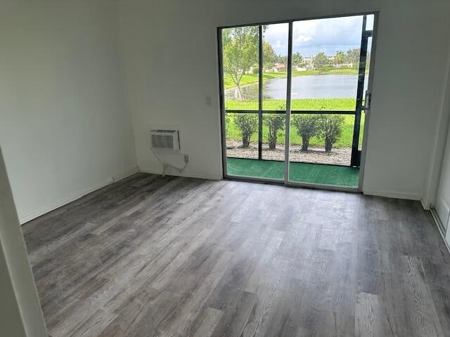 spare room with hardwood / wood-style flooring, a water view, and a wealth of natural light