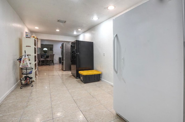 hall with a textured ceiling and light tile patterned floors