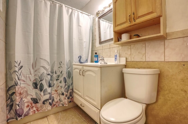 bathroom with tile walls, curtained shower, vanity, and toilet