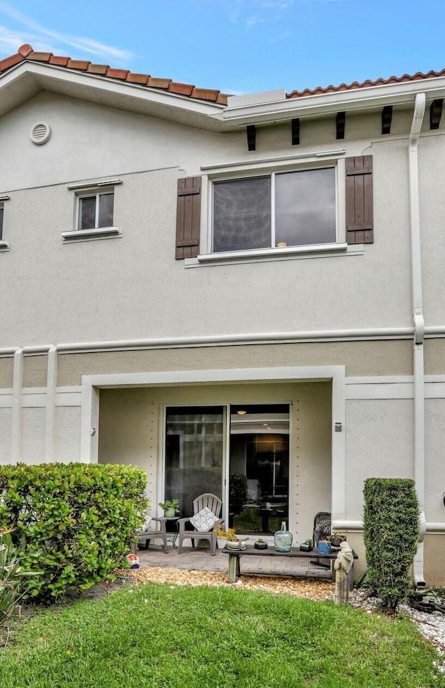 back of property featuring a patio and a lawn