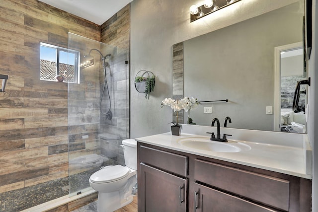 bathroom featuring toilet, vanity, and a tile shower