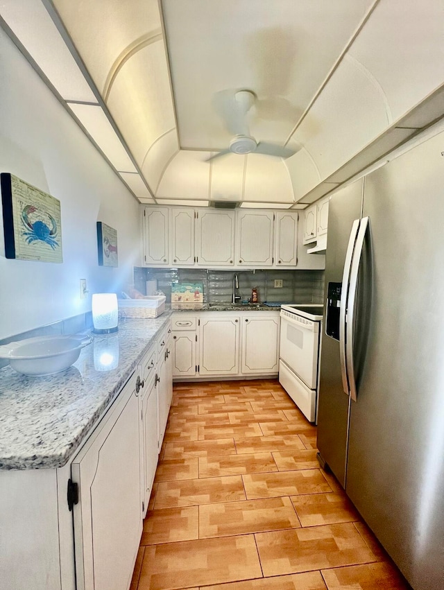 kitchen featuring light hardwood / wood-style flooring, electric range, light stone counters, white cabinetry, and stainless steel fridge