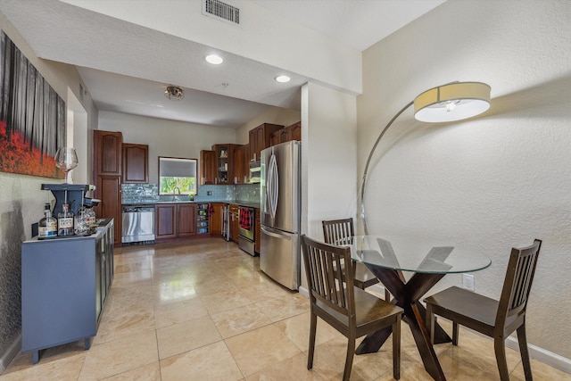 kitchen with sink, backsplash, a textured ceiling, light tile patterned floors, and appliances with stainless steel finishes