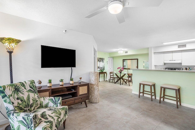 living room featuring ceiling fan and a textured ceiling