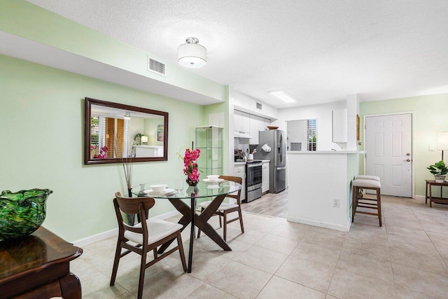 dining space with light tile patterned floors and a textured ceiling