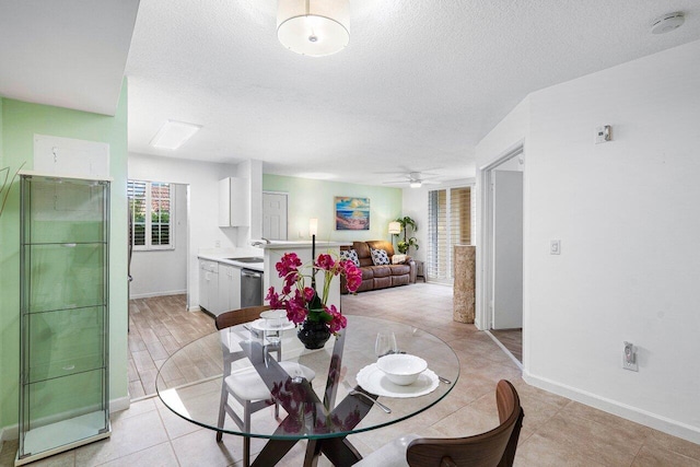 dining room featuring ceiling fan, sink, light hardwood / wood-style floors, and a textured ceiling