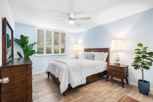 bedroom with ceiling fan, a textured ceiling, and light wood-type flooring