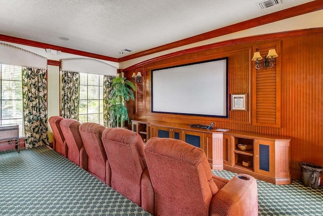 home theater room featuring a textured ceiling, wooden walls, ornamental molding, and carpet