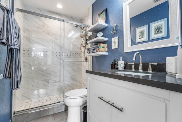 bathroom featuring tile patterned floors, vanity, toilet, and a shower with shower door