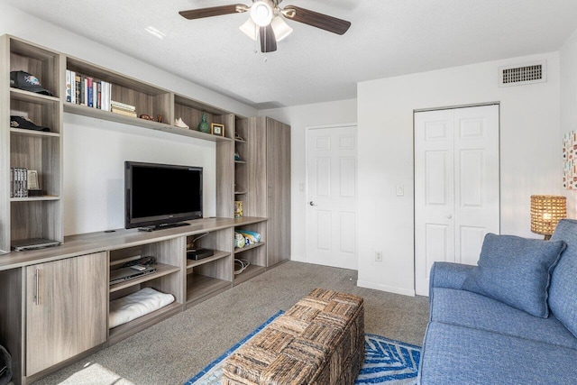 living room with ceiling fan, dark carpet, and a textured ceiling