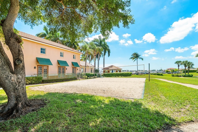 view of property's community with volleyball court and a lawn