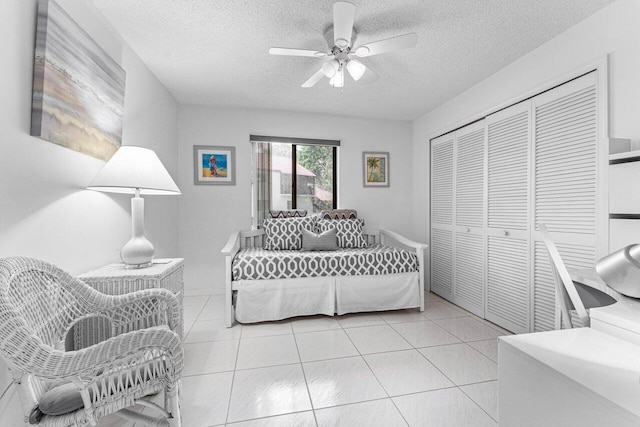 living room featuring light tile patterned flooring, ceiling fan, and a textured ceiling