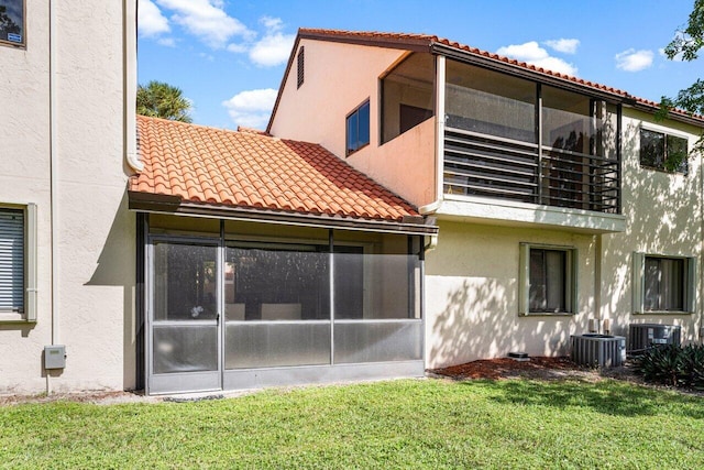 back of property with a sunroom and a yard