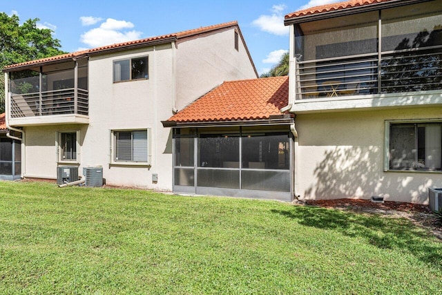 back of house with central AC unit, a sunroom, and a lawn