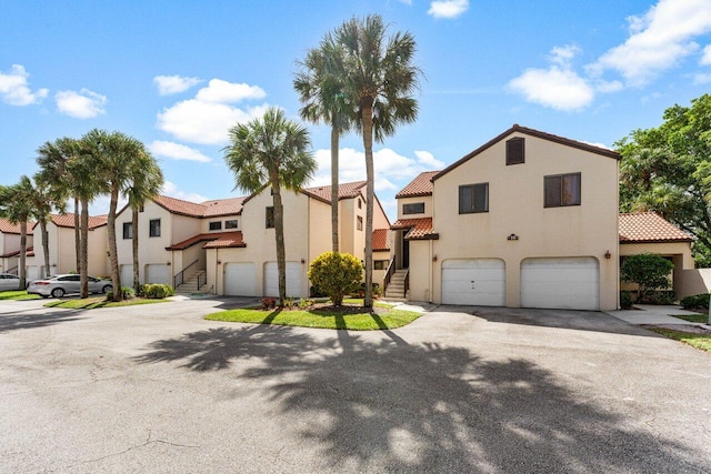 10 Via De Casas Sur Unit 104, Boynton Beach, FL 33426 - view of front of house with stucco siding, stairs, an attached garage, and a tiled roof
